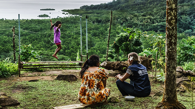 Two women watching a girl at play.