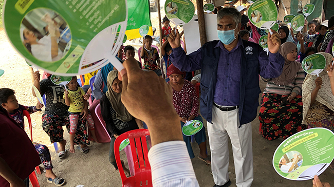 Group of people voting in Cambodia with a leader wearing a mask.