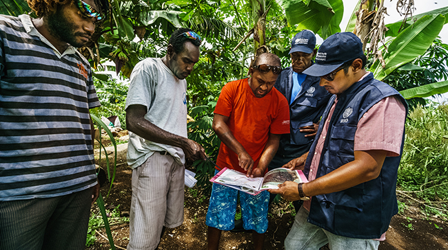 Group of Vanuatu looking at a book.