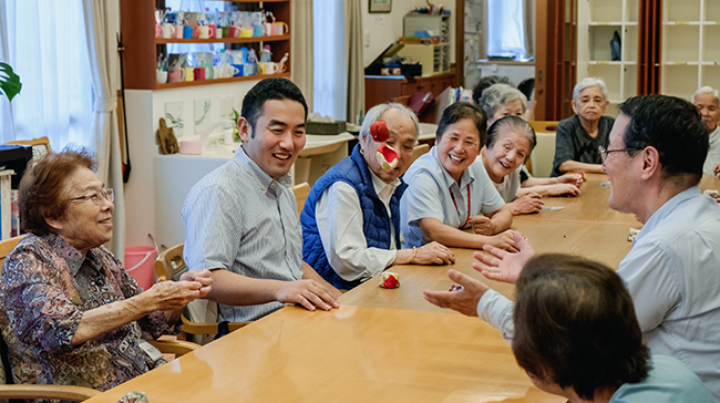 People sitting around a long conference table, tossing a small bean bag.